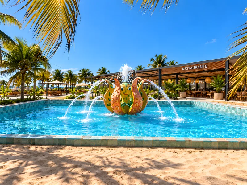 Piscina com fonte central e coqueiros